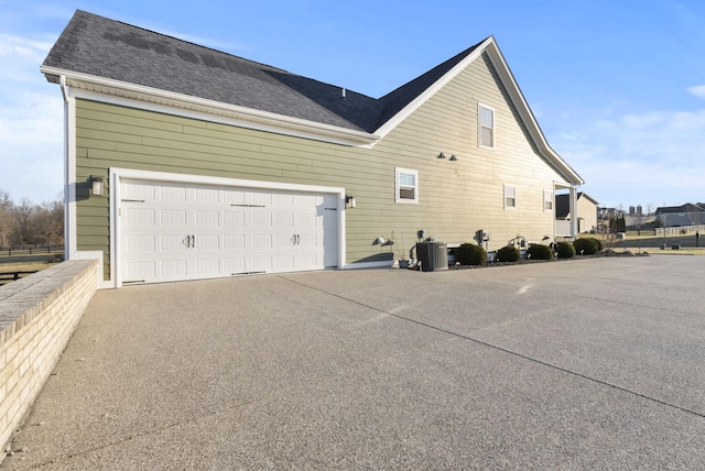 view of property exterior with cooling unit, driveway, and roof with shingles