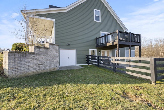 rear view of property with french doors, a wooden deck, a yard, and fence