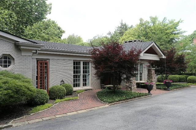 view of front of property featuring brick siding and a shingled roof