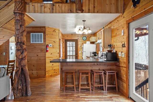 225 Platinum Dr, Slade, KY 40376 - kitchen with dark countertops, wooden walls, light wood-style flooring, stainless steel microwave, and visible vents