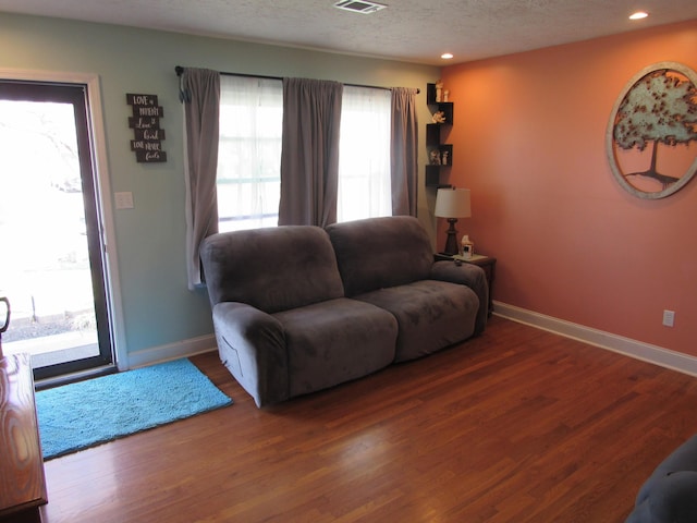 living room with wood finished floors, visible vents, baseboards, recessed lighting, and a textured ceiling