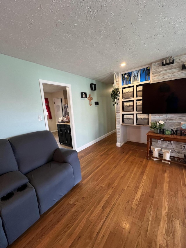 living area with a textured ceiling, baseboards, and wood finished floors