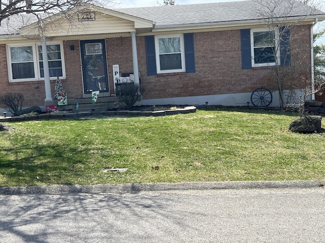 view of front of house featuring a front yard, brick siding, and roof with shingles