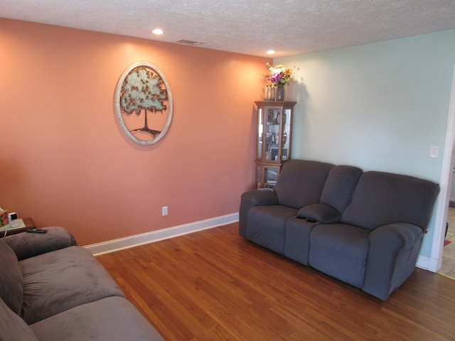 living area featuring visible vents, a textured ceiling, wood finished floors, recessed lighting, and baseboards