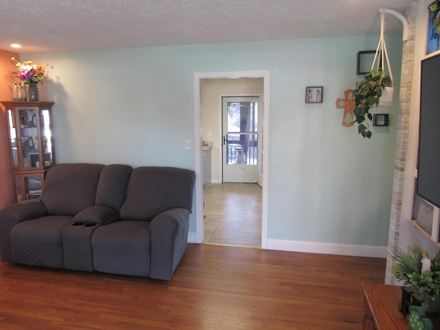 living room featuring baseboards, a textured ceiling, and wood finished floors