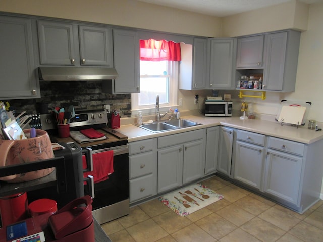 kitchen featuring gray cabinetry, under cabinet range hood, light countertops, stainless steel appliances, and a sink