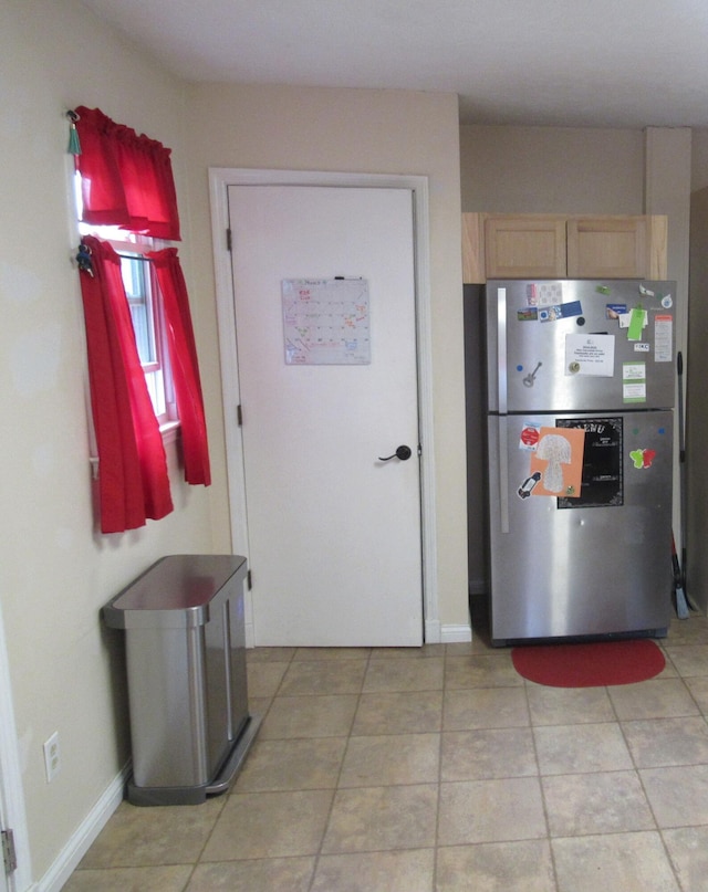 kitchen featuring light tile patterned floors, freestanding refrigerator, and baseboards