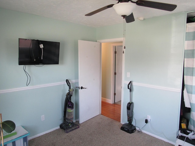 interior space featuring carpet, ceiling fan, and a textured ceiling