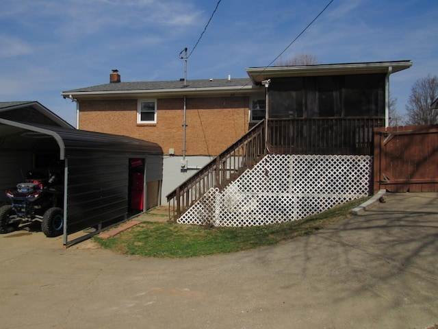 rear view of property featuring brick siding, a chimney, and a sunroom