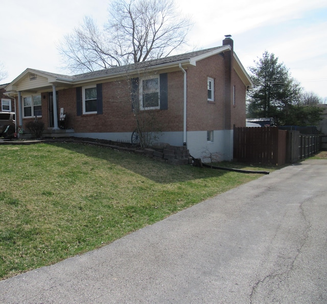 ranch-style house featuring a front yard, fence, brick siding, and a chimney