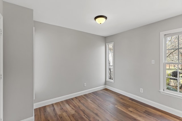 empty room with baseboards and dark wood-style floors