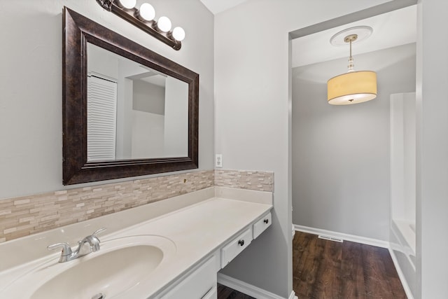 full bathroom with baseboards, a washtub, decorative backsplash, wood finished floors, and vanity