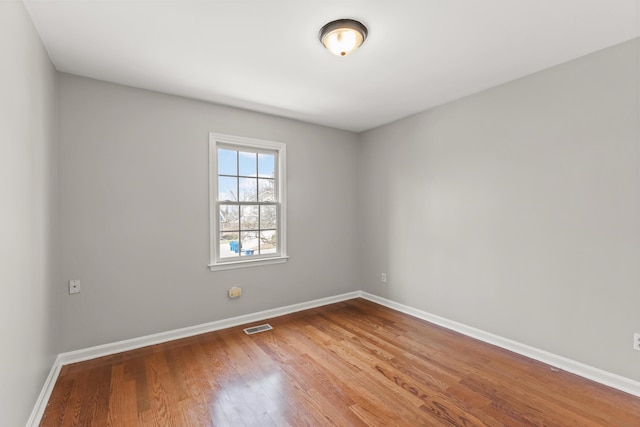 unfurnished room with visible vents, baseboards, and wood finished floors