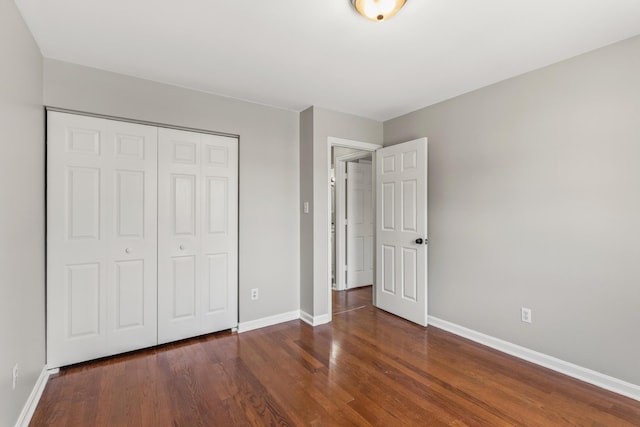 unfurnished bedroom with a closet, baseboards, and wood finished floors