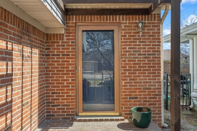 view of exterior entry featuring brick siding