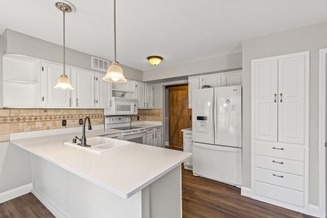 kitchen featuring open shelves, light countertops, a peninsula, white appliances, and a sink