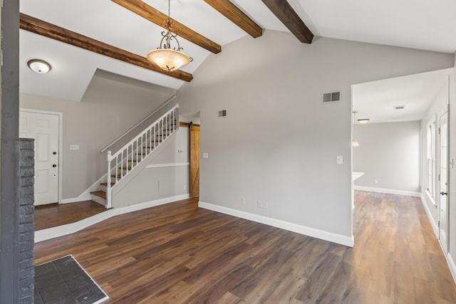 unfurnished living room featuring visible vents, vaulted ceiling with beams, a barn door, and wood finished floors