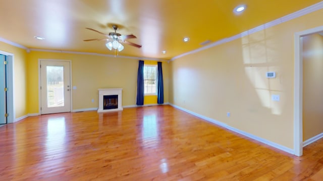 unfurnished living room with a glass covered fireplace, light wood-style flooring, crown molding, and baseboards