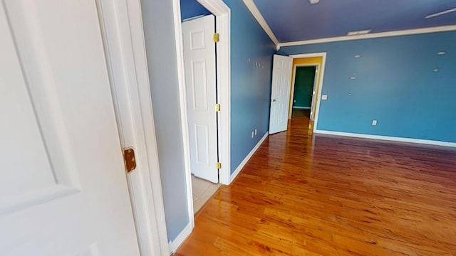 interior space featuring baseboards, wood finished floors, and crown molding