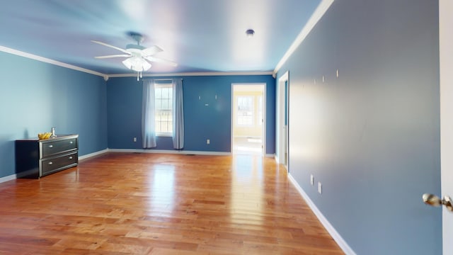 spare room featuring baseboards, light wood-style flooring, a ceiling fan, and ornamental molding