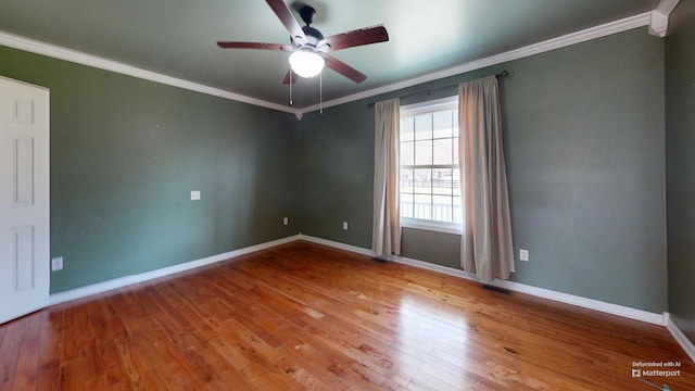 unfurnished room with a ceiling fan, wood finished floors, baseboards, visible vents, and crown molding