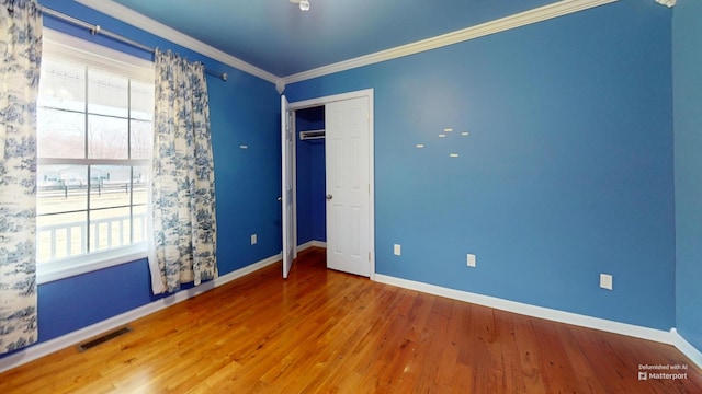 unfurnished bedroom with crown molding, wood finished floors, visible vents, and baseboards