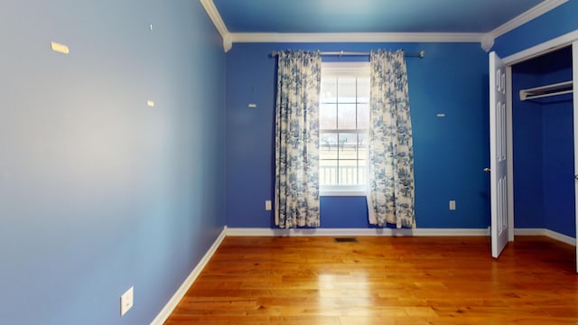 unfurnished bedroom with visible vents, crown molding, baseboards, and wood finished floors