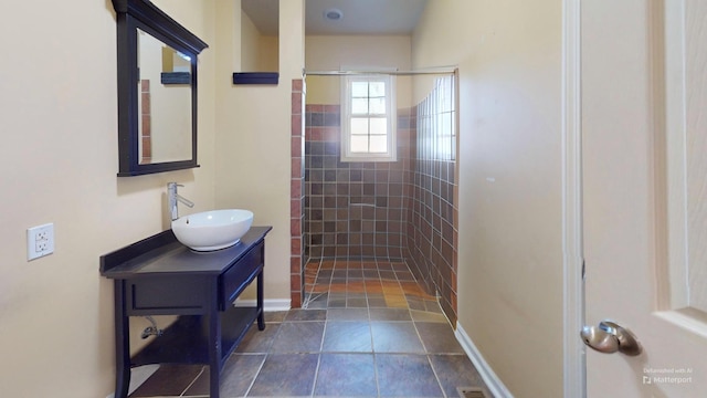 bathroom with tiled shower and vanity