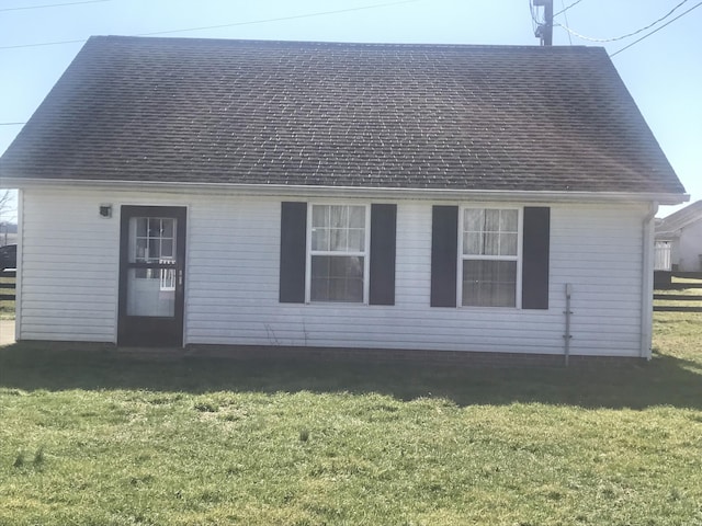 rear view of property with a lawn and roof with shingles