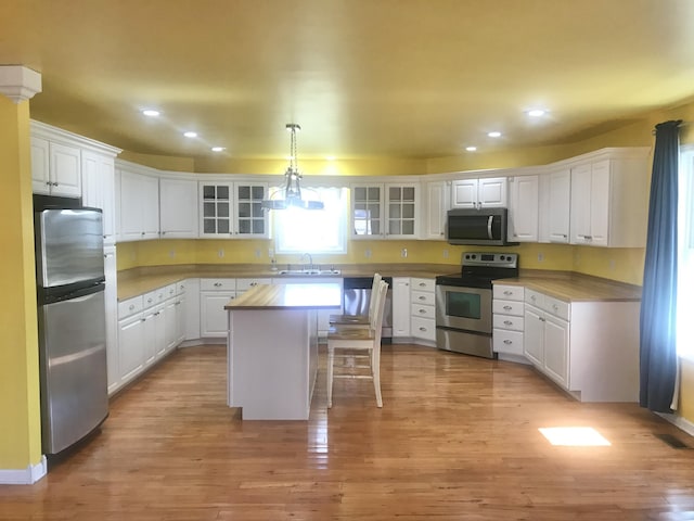 kitchen with white cabinetry, light wood-style flooring, appliances with stainless steel finishes, and a sink