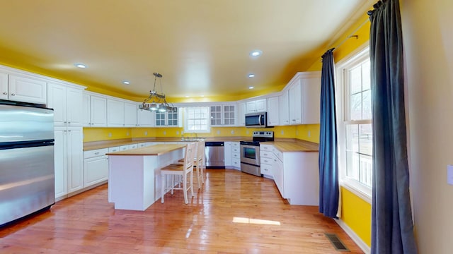 kitchen featuring white cabinets, appliances with stainless steel finishes, and butcher block countertops