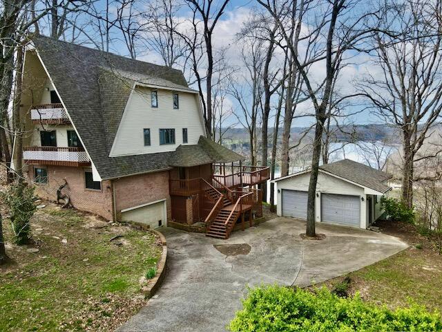 view of home's exterior with stairs, an outdoor structure, a garage, and a shingled roof