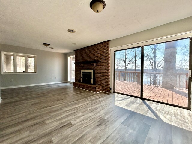 3101 Simpson Dr, Somerset, KY 42503 - unfurnished living room featuring a brick fireplace, plenty of natural light, wood finished floors, and baseboards