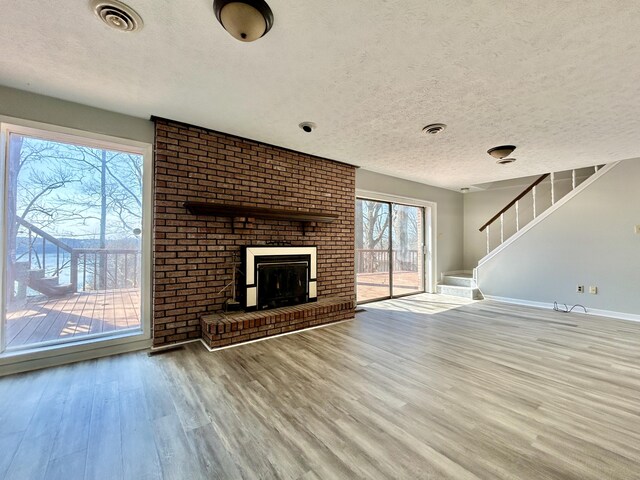 3101 Simpson Dr, Somerset, KY 42503 - unfurnished living room featuring visible vents, a fireplace, stairs, and wood finished floors