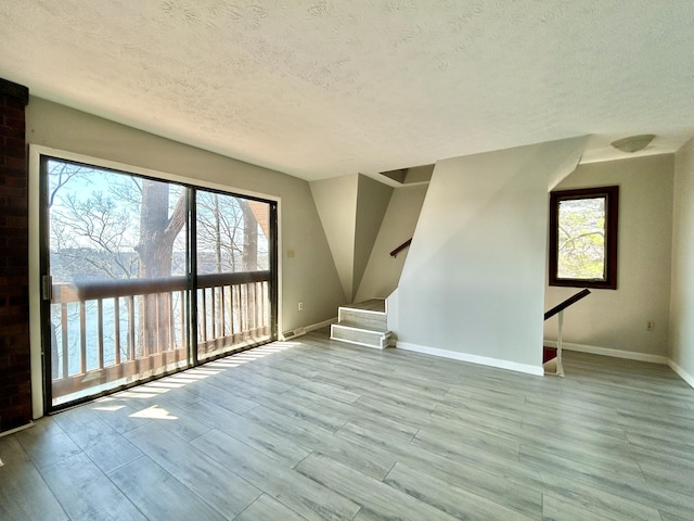 3101 Simpson Dr, Somerset, KY 42503 - unfurnished living room with a textured ceiling, stairs, baseboards, and wood finished floors