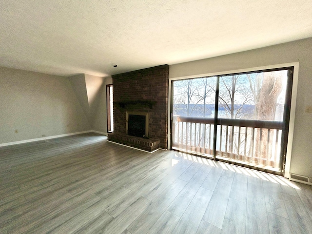 3101 Simpson Dr, Somerset, KY 42503 - unfurnished living room featuring a brick fireplace, a textured ceiling, baseboards, and wood finished floors