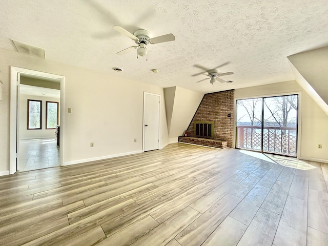 3101 Simpson Dr, Somerset, KY 42503 - unfurnished living room featuring light wood-type flooring, a textured ceiling, a brick fireplace, and a ceiling fan