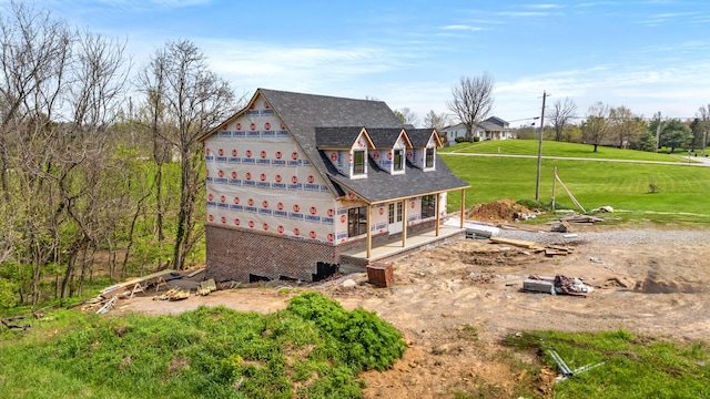 back of house featuring a shingled roof and a lawn