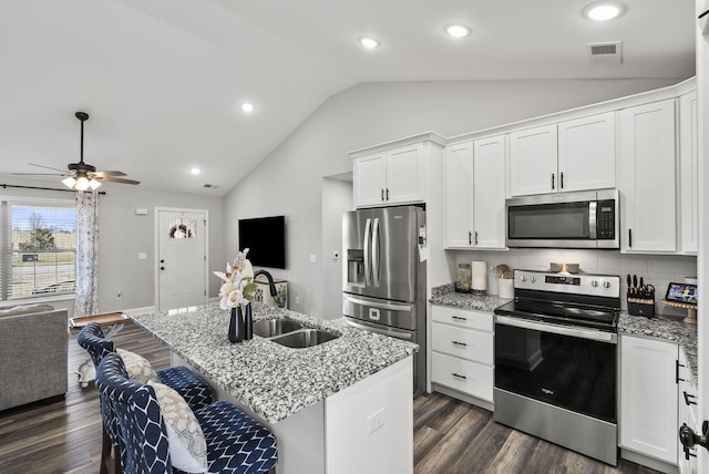 kitchen with open floor plan, white cabinets, appliances with stainless steel finishes, and a sink