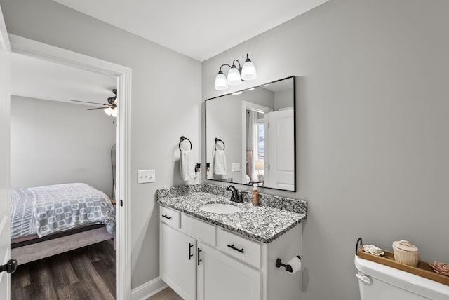 ensuite bathroom with vanity, wood finished floors, a ceiling fan, ensuite bath, and toilet