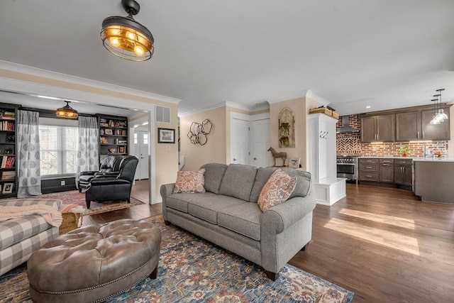 living area with dark wood finished floors, crown molding, and visible vents