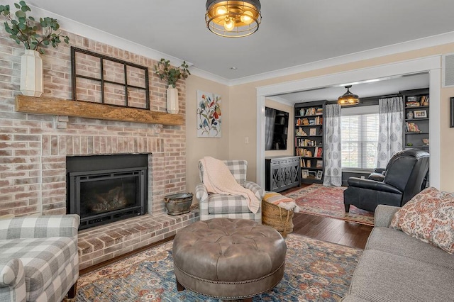 living area with wood finished floors, ornamental molding, and a fireplace