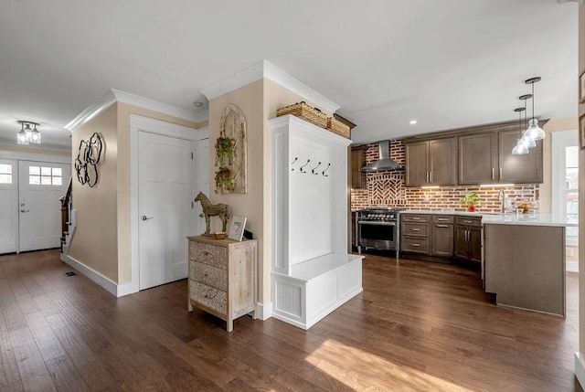 kitchen with high end stove, a sink, wall chimney range hood, dark wood-style floors, and light countertops