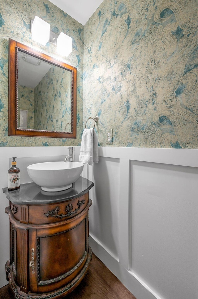 bathroom featuring wallpapered walls, wood finished floors, and vanity