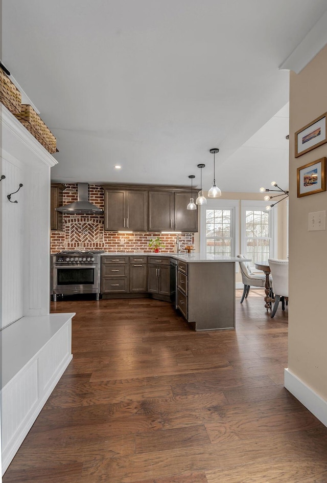 kitchen with a peninsula, dark wood-type flooring, high end stainless steel range, wall chimney range hood, and tasteful backsplash