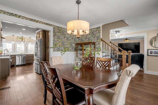 dining area with dark wood finished floors, a notable chandelier, wallpapered walls, and crown molding