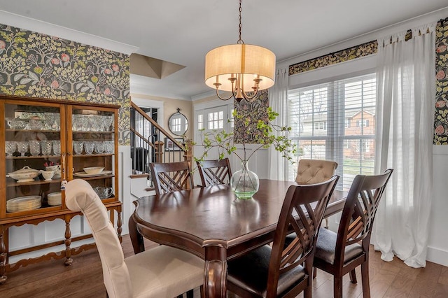 dining room featuring a healthy amount of sunlight, wood finished floors, an inviting chandelier, and ornamental molding