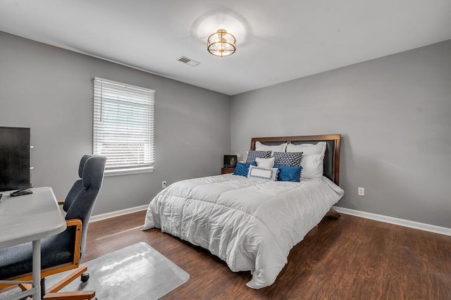 bedroom with visible vents, baseboards, and wood finished floors