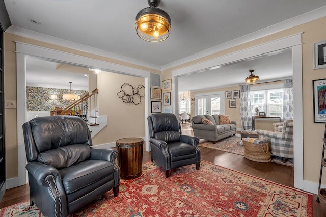 living room featuring stairway, an inviting chandelier, wood finished floors, and crown molding