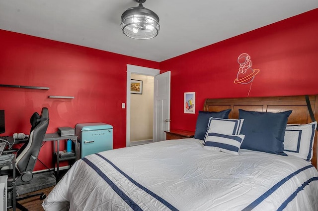 bedroom featuring fridge and an accent wall